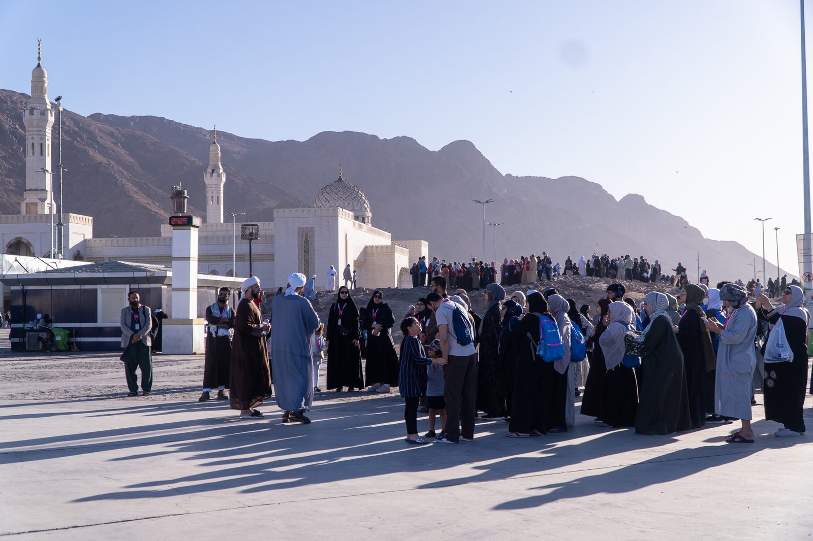 Pilgrims gathered with the Madinah mountains behind them