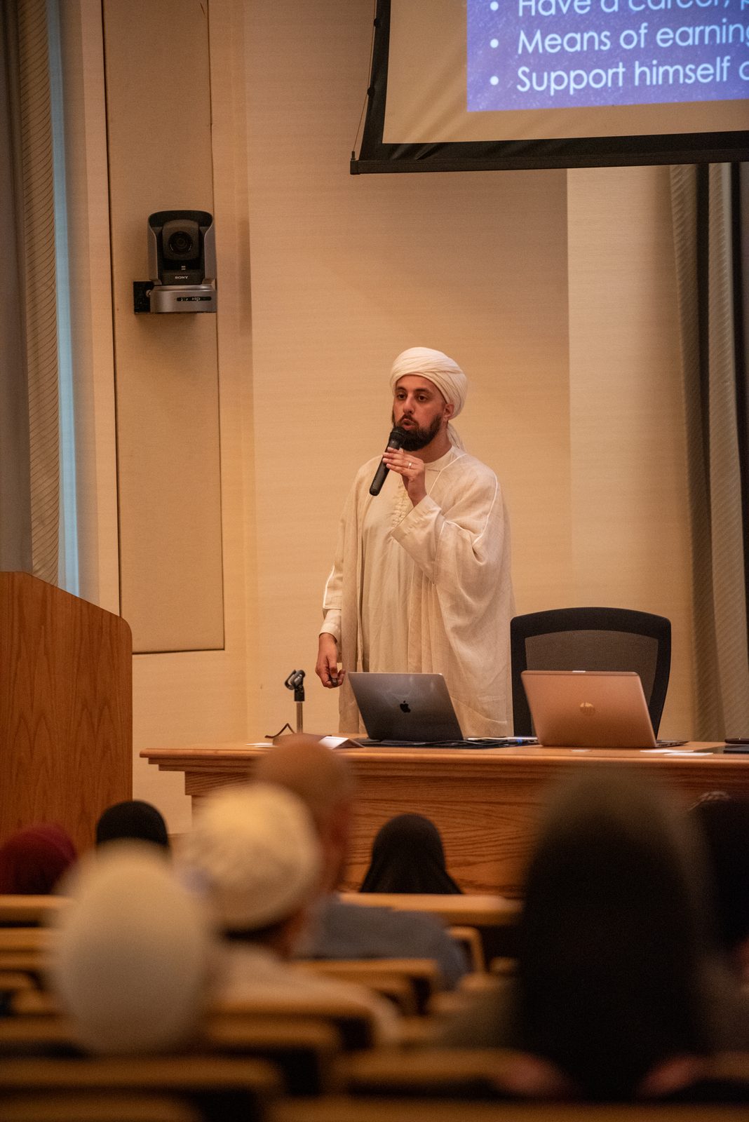 A scholar delivering a lecture at the podium